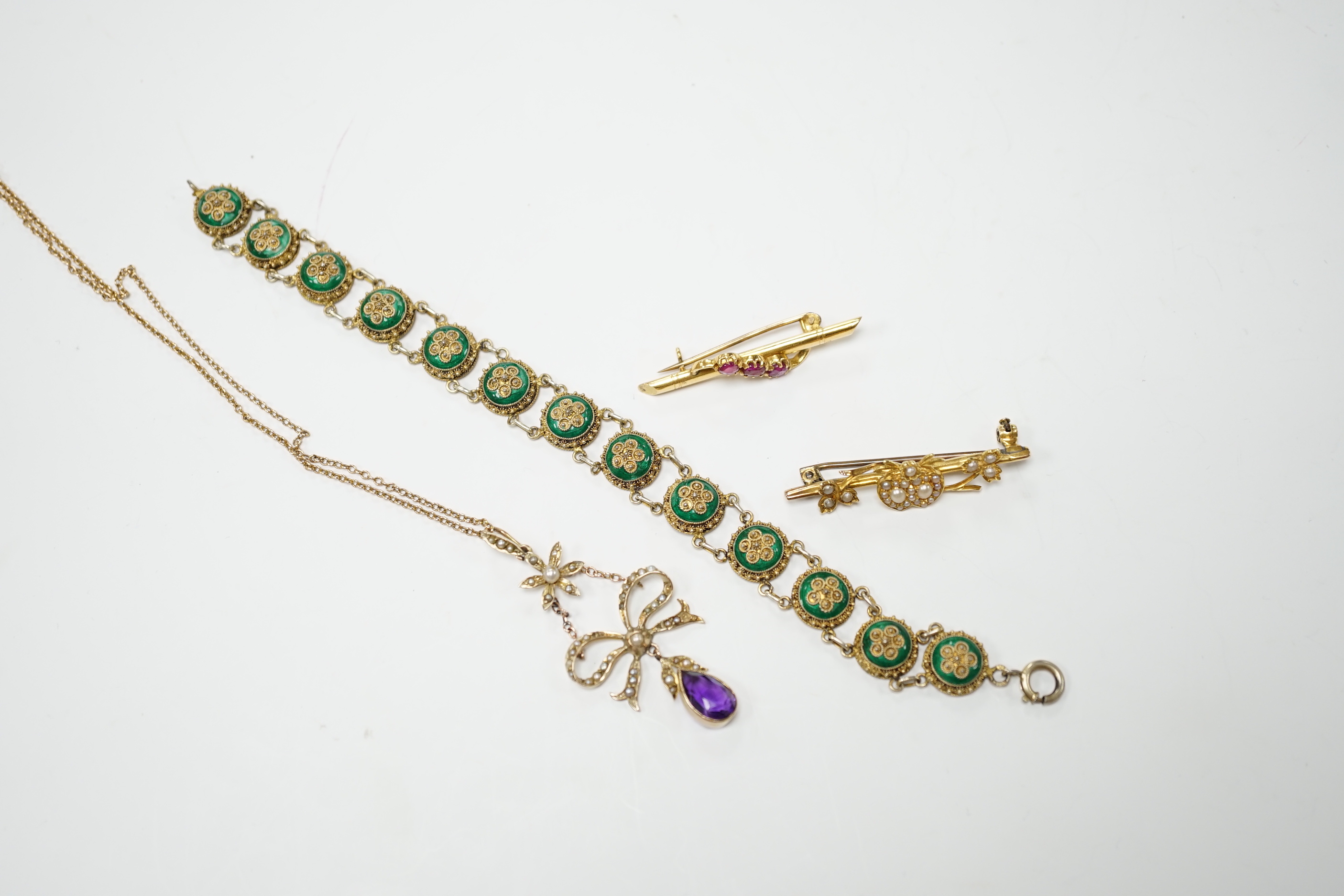 An Edwardian yellow metal, amethyst and split pearl set drop pendant, 52mm, on a yellow metal fine link chain, 45cm, a similar yellow metal and seed pearl set twin hearts bar brooch, a yellow metal and three stone ruby s